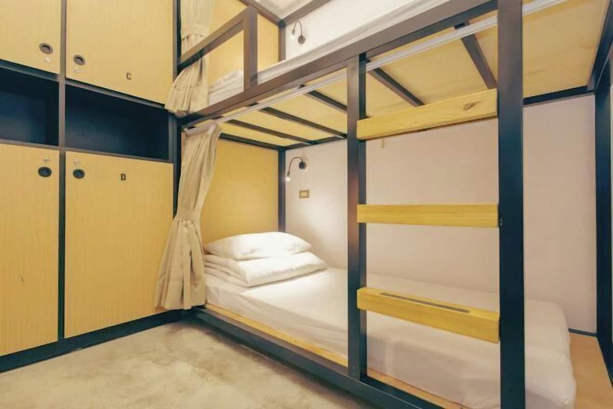 A bunk bed room with wooden bunk beds, a single bed, and a wardrobe with multiple compartments.
