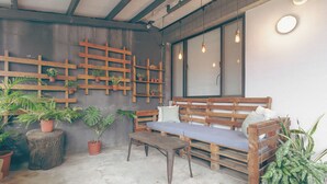 A rustic interior with wooden benches, potted plants, and a concrete floor. - DONGMEN 3 Capsule Inn - Hostel (Taipei)