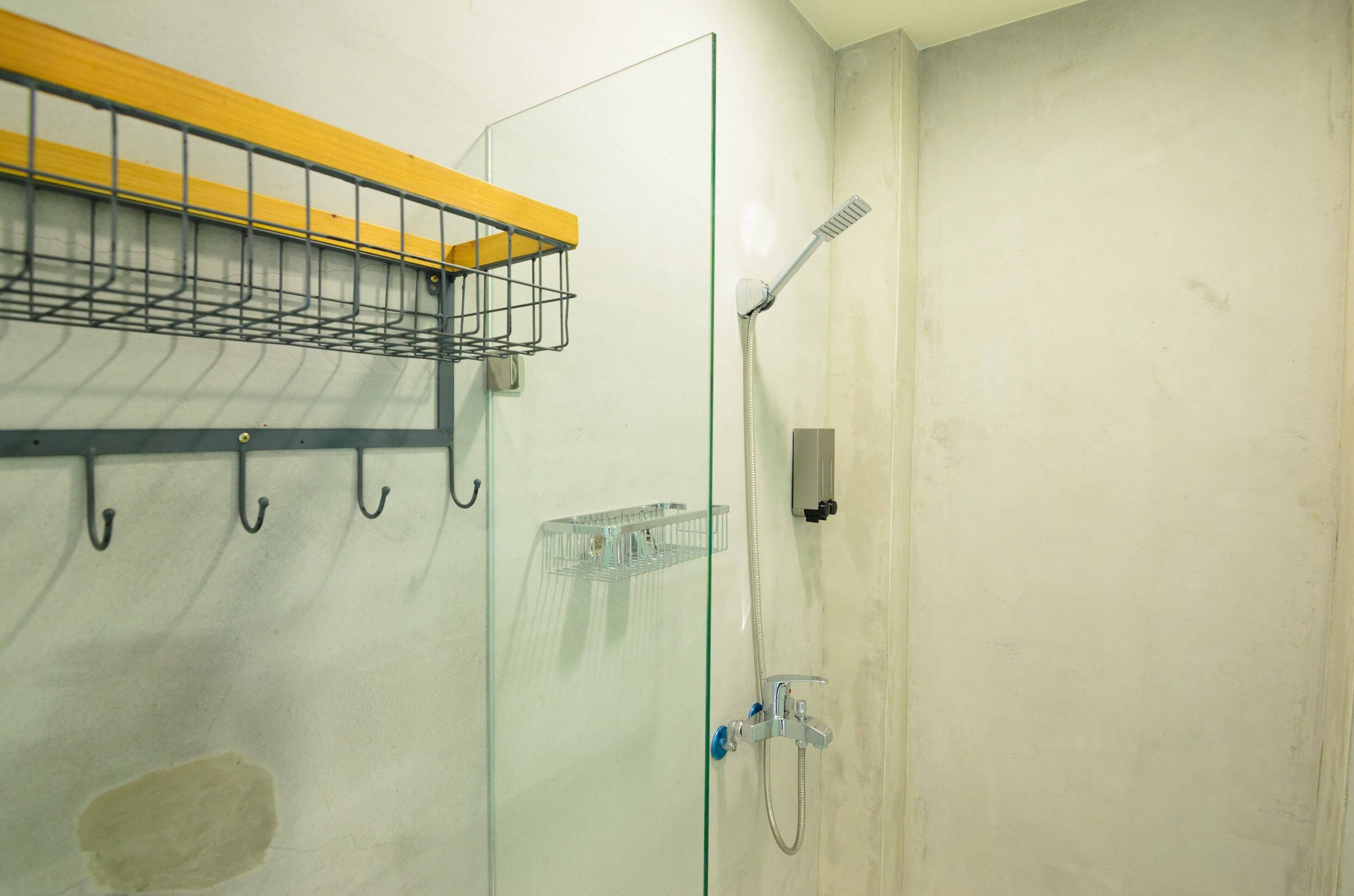A glass shower enclosure with a handheld showerhead and a wall-mounted faucet.
