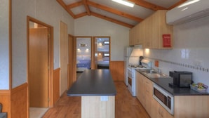 A compact kitchen with wooden cabinets, a countertop, and a stove. - Yea Riverside Caravan Park (Yea)