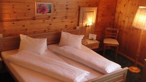 A double bed with two pillows and a nightstand with a lamp. - Hotel Chalet Bergblick (Aeschi bei Spiez)