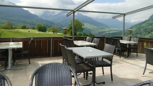 An outdoor patio with tables and chairs, overlooking a mountainous landscape. - Hotel Chalet Bergblick (Aeschi bei Spiez)