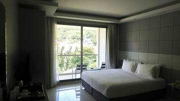 Una habitación de hotel moderna con una cama grande, un balcón con vistas a zonas verdes y un televisor de pantalla plana.