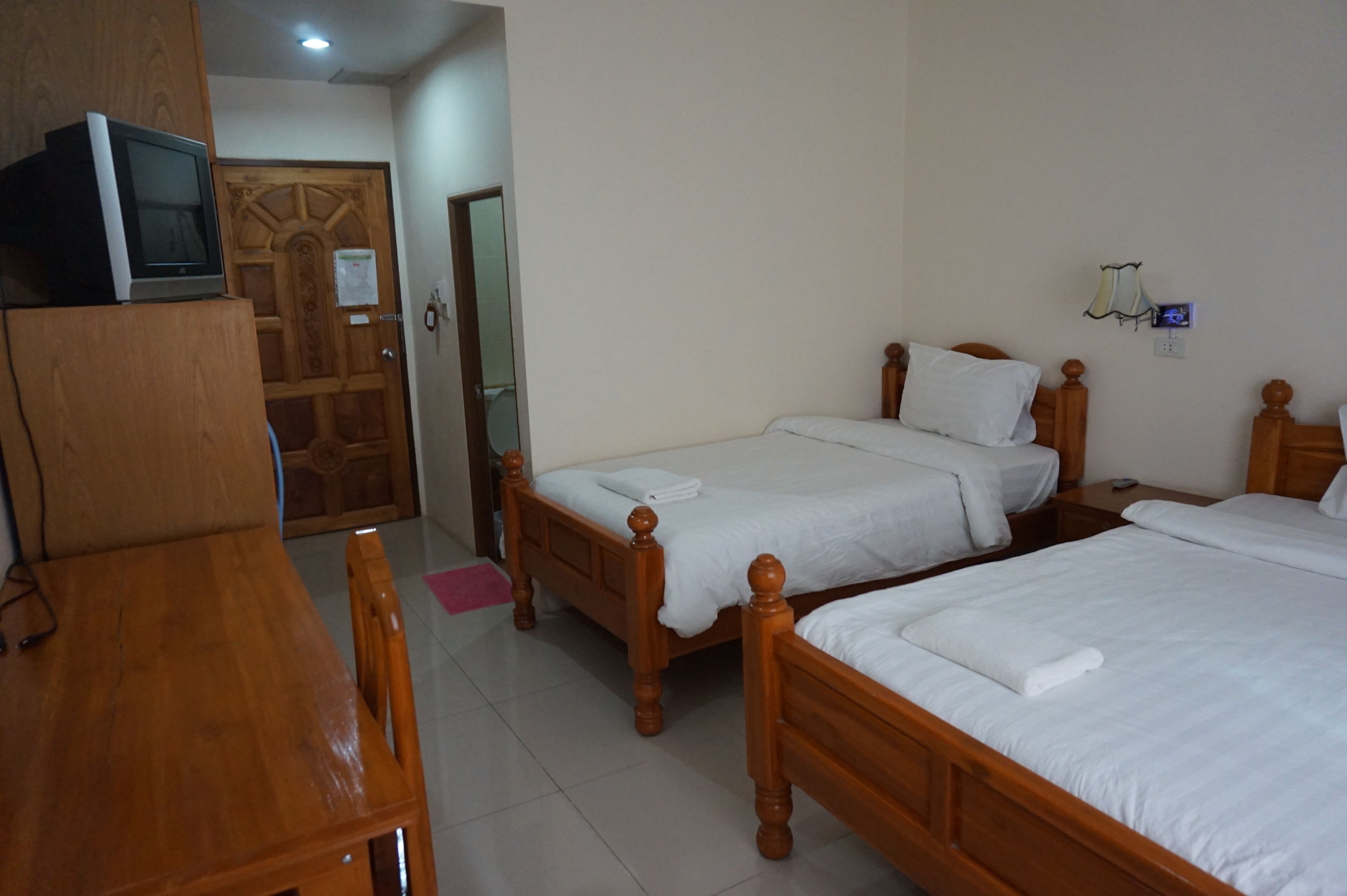 A hotel room with two wooden beds, a wooden desk, and a television on a cabinet.