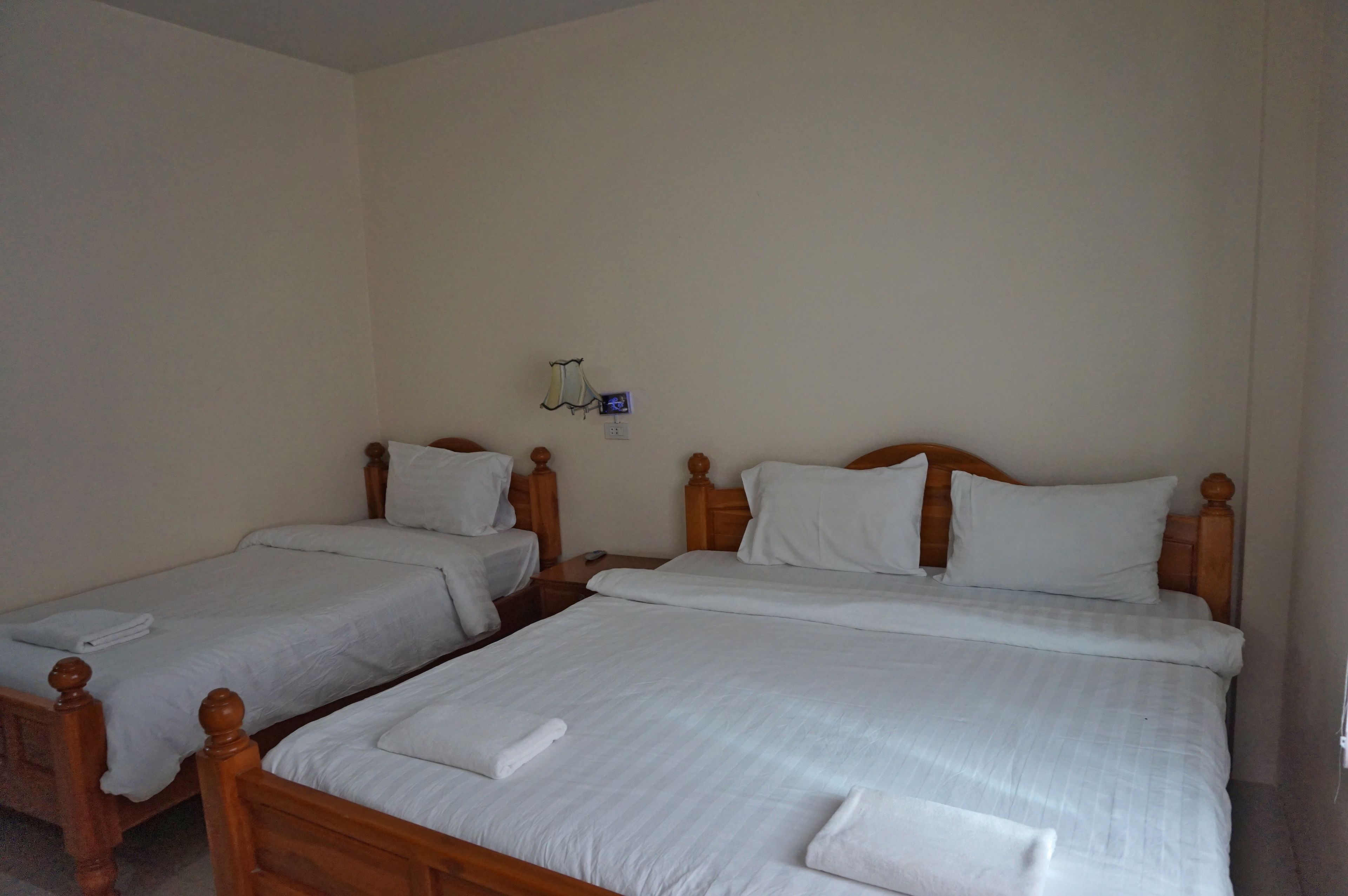 Habitación de hotel con dos camas individuales, cada una con cabeceros de madera y ropa de cama blanca.