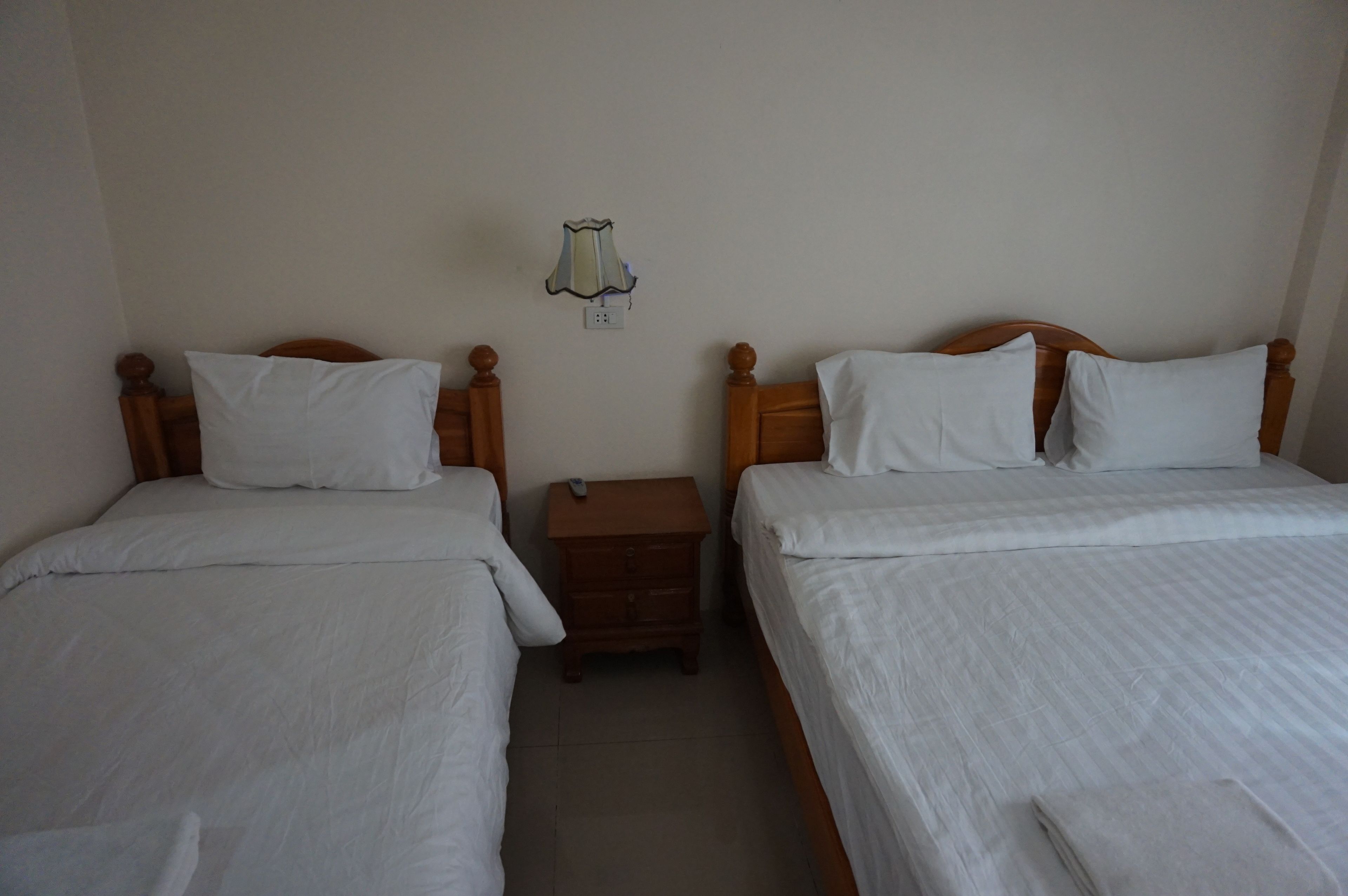 A twin room with two single beds, a nightstand, and a wall-mounted lamp.