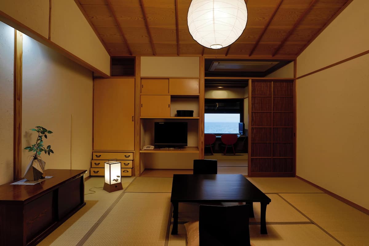A traditional Japanese room with tatami flooring, a low table, and a television.