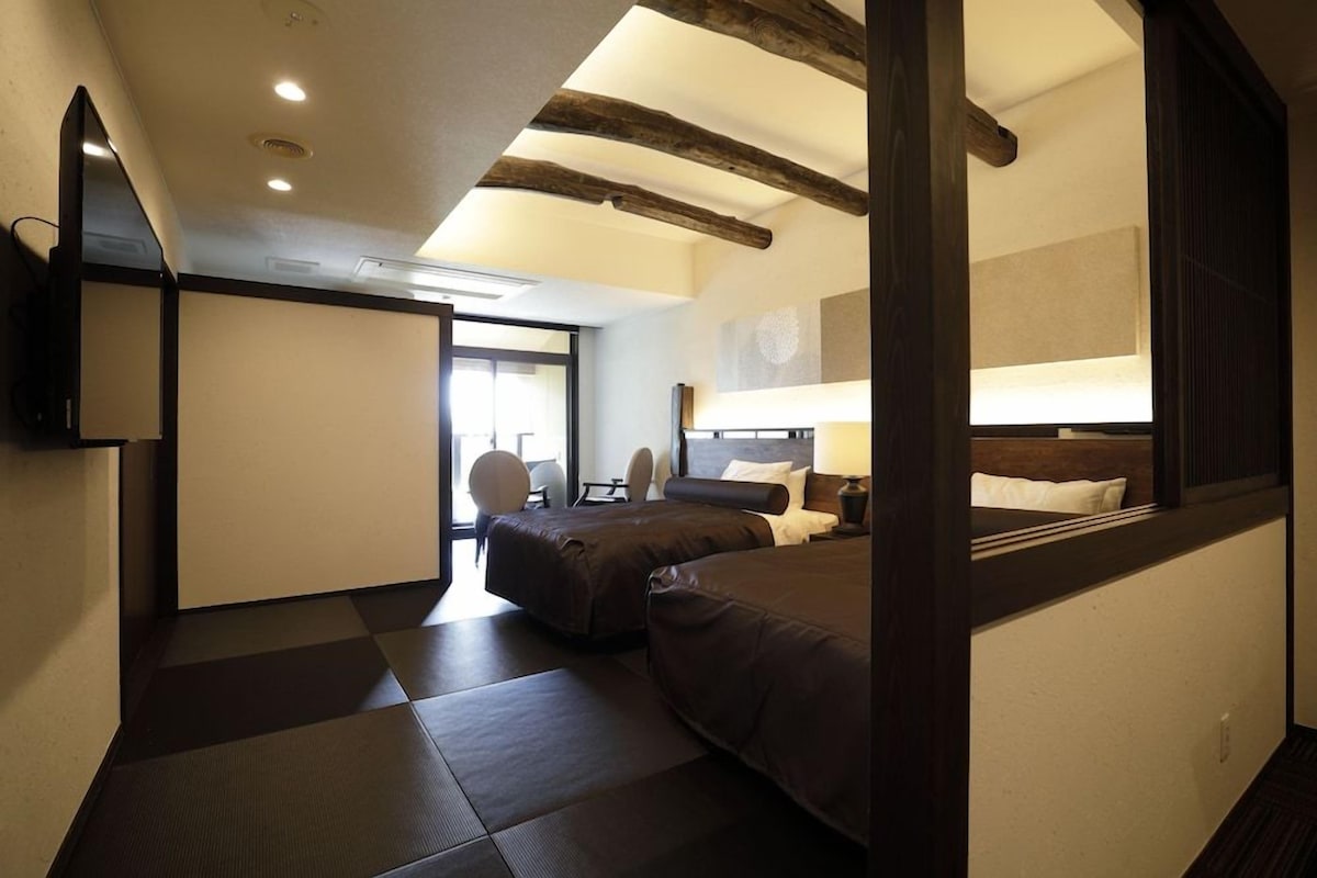 A hotel room with a bed, a desk, a chair, and a large window.