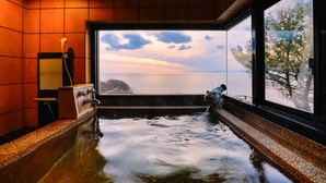 A hot tub with a view of the sea and a snowy landscape through a large window. - Hotel Isaba (Numazu)