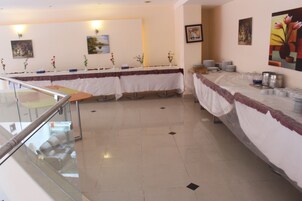 Un salón de conferencias con una larga mesa cubierta con un mantel blanco, rodeada de sillas.