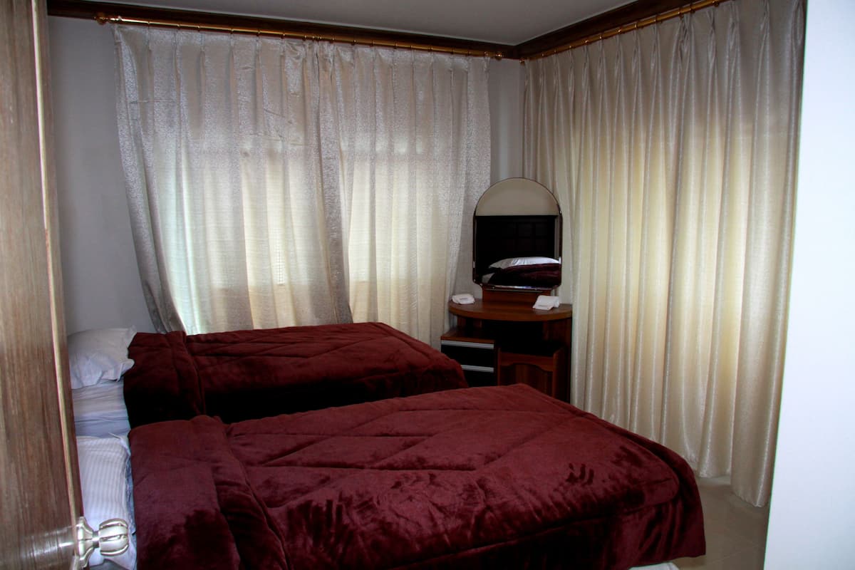 A hotel room with two beds, a desk, and a mirror.