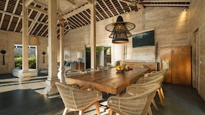 A spacious dining area with a large wooden table, wicker chairs, and a modern pendant light. - Villa Alea by Villa Finder (Kerobokan)