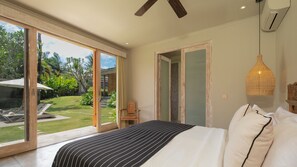 A bedroom with a large bed, a view of a garden, and a sliding door leading to an outdoor area. - Villa Alea by Villa Finder (Kerobokan)