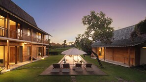Un edificio de dos pisos con balcón, piscina y mobiliario exterior.