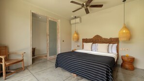 A bedroom with a bed, a wooden chair, a ceiling fan, and a wall-mounted air conditioner. - Villa Alea by Villa Finder (Kerobokan)