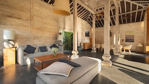 Una habitación amplia con un sofá grande, una mesa de centro y sillas de mimbre.