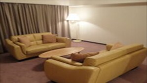 A room with a yellow sofa set, a small coffee table, and a lamp.