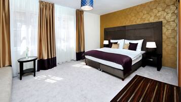 A hotel room with a large bed, two bedside tables, a round side table, a wooden coffee table, and a patterned wall.