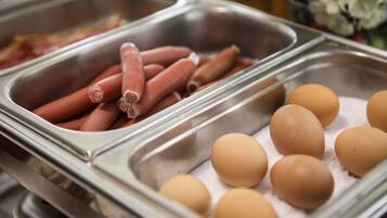 Un bufé con bandejas de hot dogs y huevos.