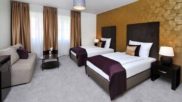 A hotel room with two beds, a sofa, a small table, and a lamp.