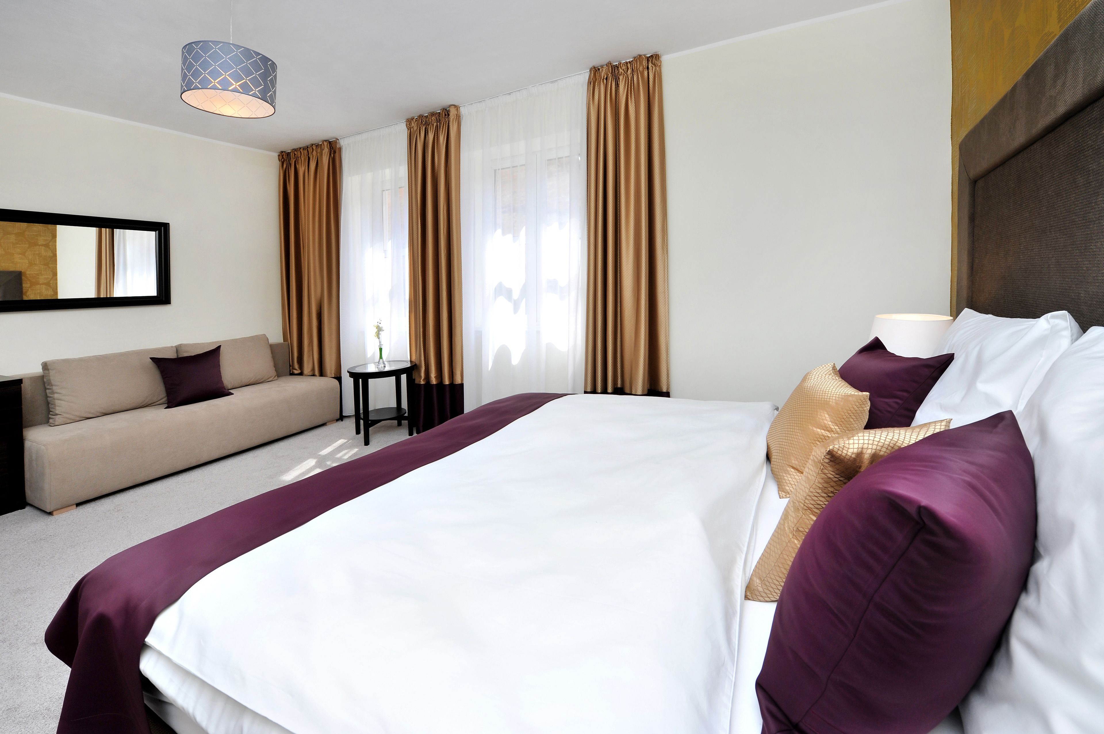 Une chambre d’hôtel avec un grand lit, un canapé, une petite table et une lampe.