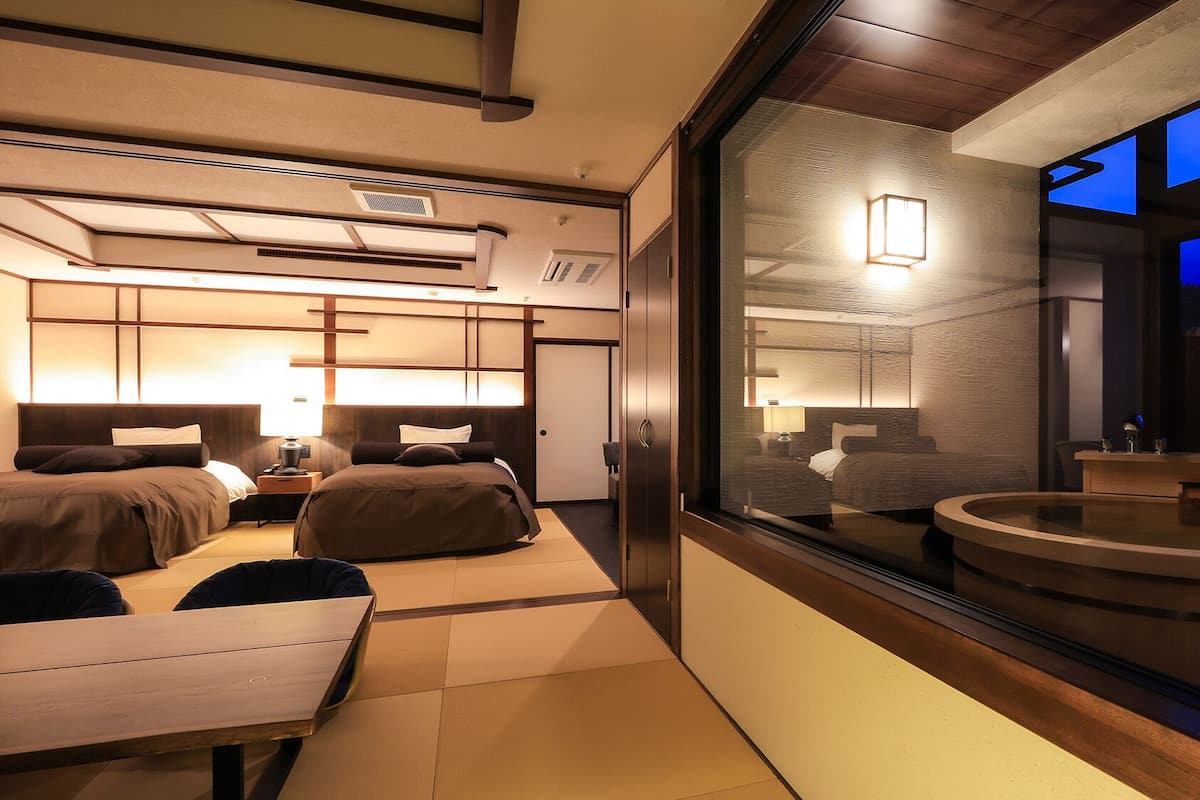 A modern hotel room with a large bed, a desk, and a view of the outside.