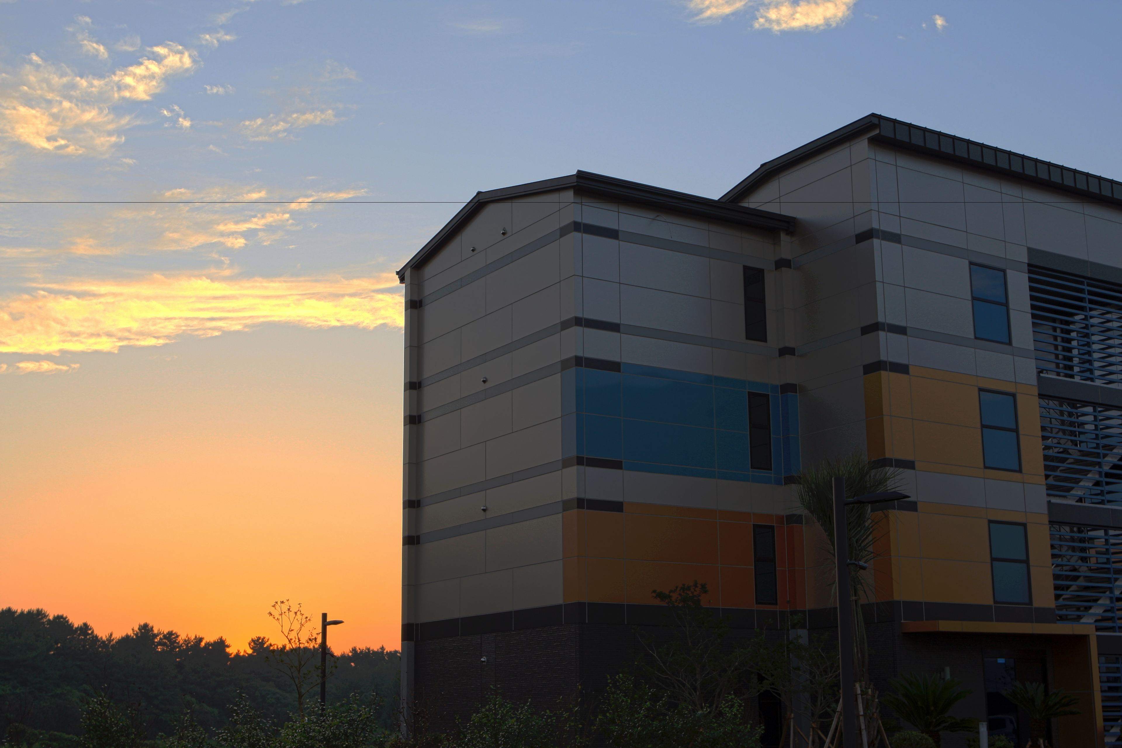 A modern building with a flat roof and a mix of rectangular and square windows.