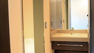 A modern bathroom with a large mirror, a sink, and a toilet.
