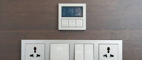 A digital thermostat and a control panel with switches and labels.
