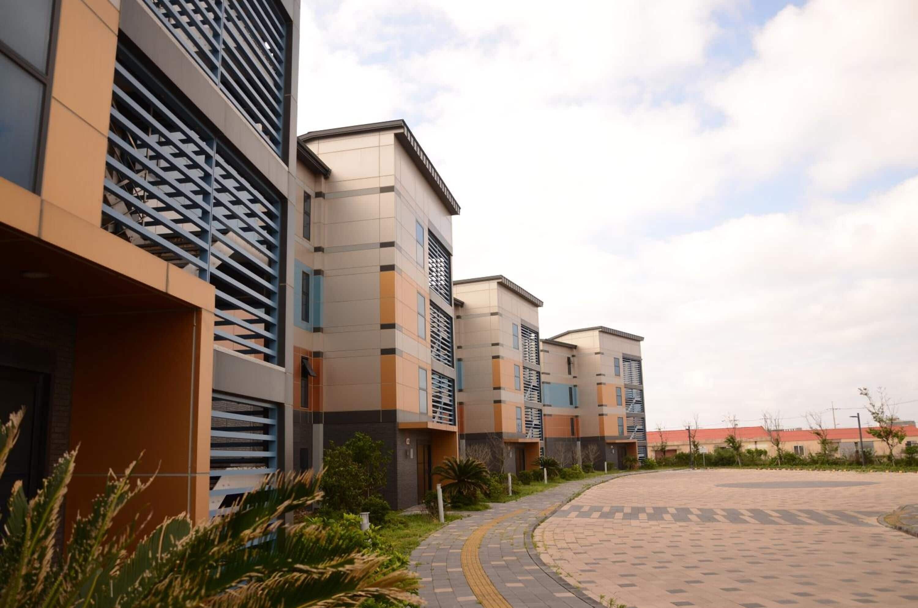 A modern residential building with a curved driveway and a landscaped area.