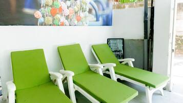 Un salon d’hôtel avec des fauteuils à coussins verts et une grande affiche publicitaire pour l’hôtel.