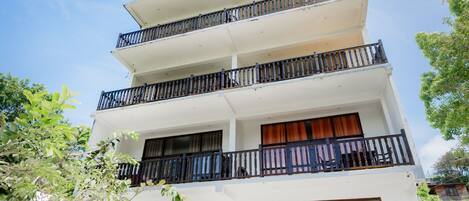 A multi-story building with balconies, a checkered floor, and a clear sky.