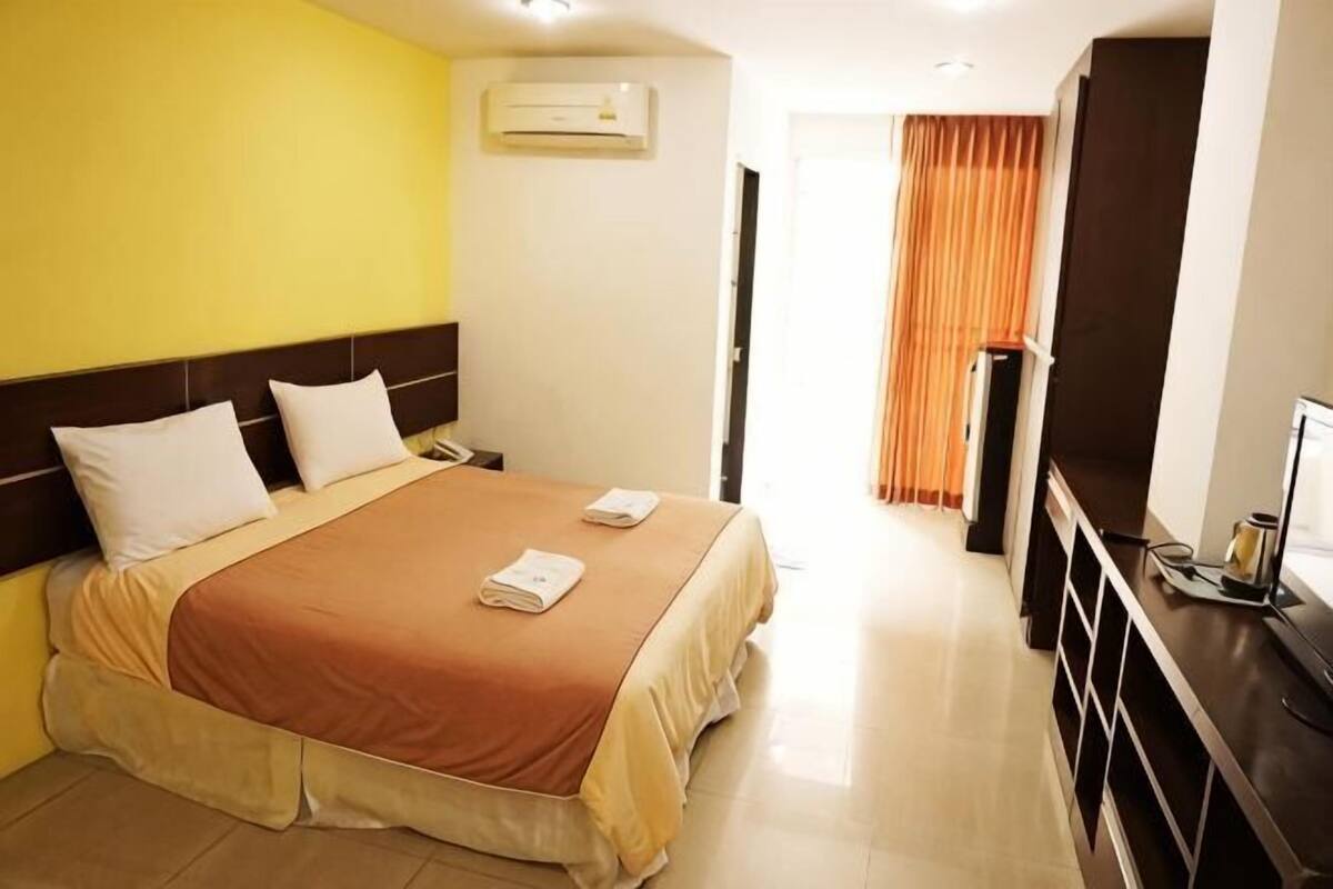 A hotel room with a bed, a desk, and a TV.