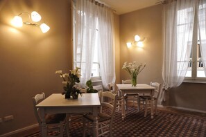 A dining area with two tables, white chairs, and a checkered floor. - Villa Anna (Lucca)