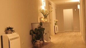 A hallway with wooden flooring, a white air conditioner, and potted plants. - Villa Anna (Lucca)