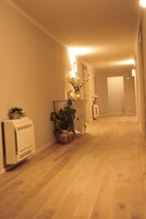 Un corridoio con pavimento in legno, condizionatore d'aria bianco e piante in vaso.