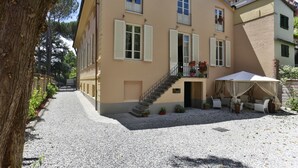 A two-story building with a gravel courtyard, a staircase leading to the upper floor, and outdoor seating with a table and chairs. - Villa Anna (Lucca)