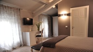 A bedroom with a bed, a desk, a chair, a television, and a door. - Villa Anna (Lucca)