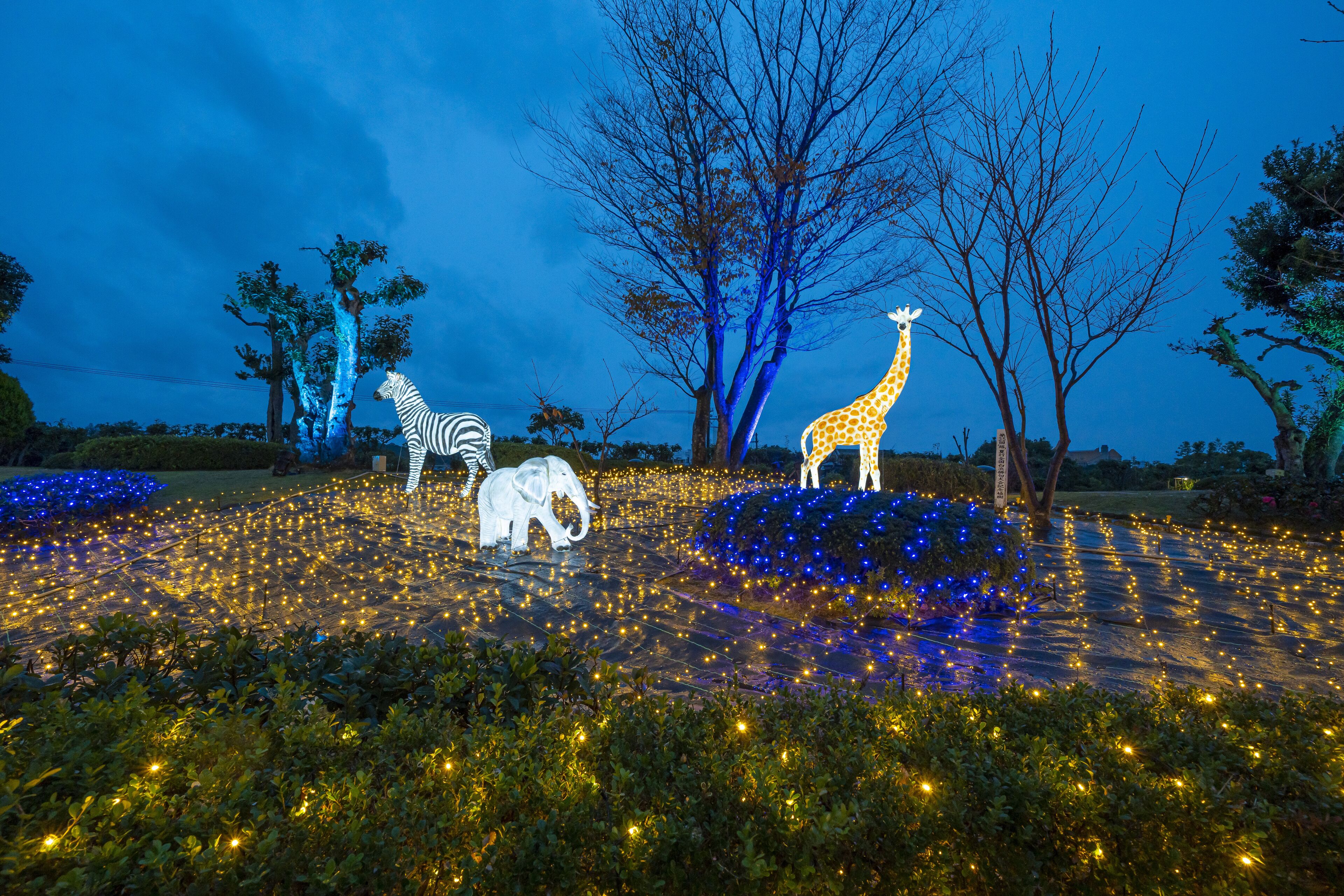 A nighttime scene with illuminated animal sculptures and trees.