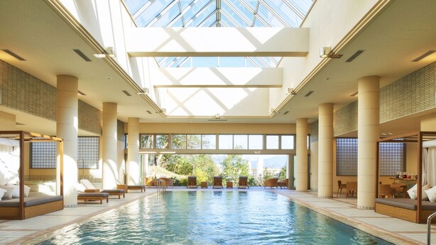 An indoor swimming pool with sunlit ceiling and seating areas on both sides. - Shirahama Coganoi Resort&Spa (Shirahama)