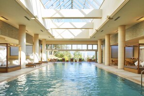 An indoor swimming pool with sunlit ceiling and seating areas on both sides. - Shirahama Coganoi Resort&Spa (Shirahama)