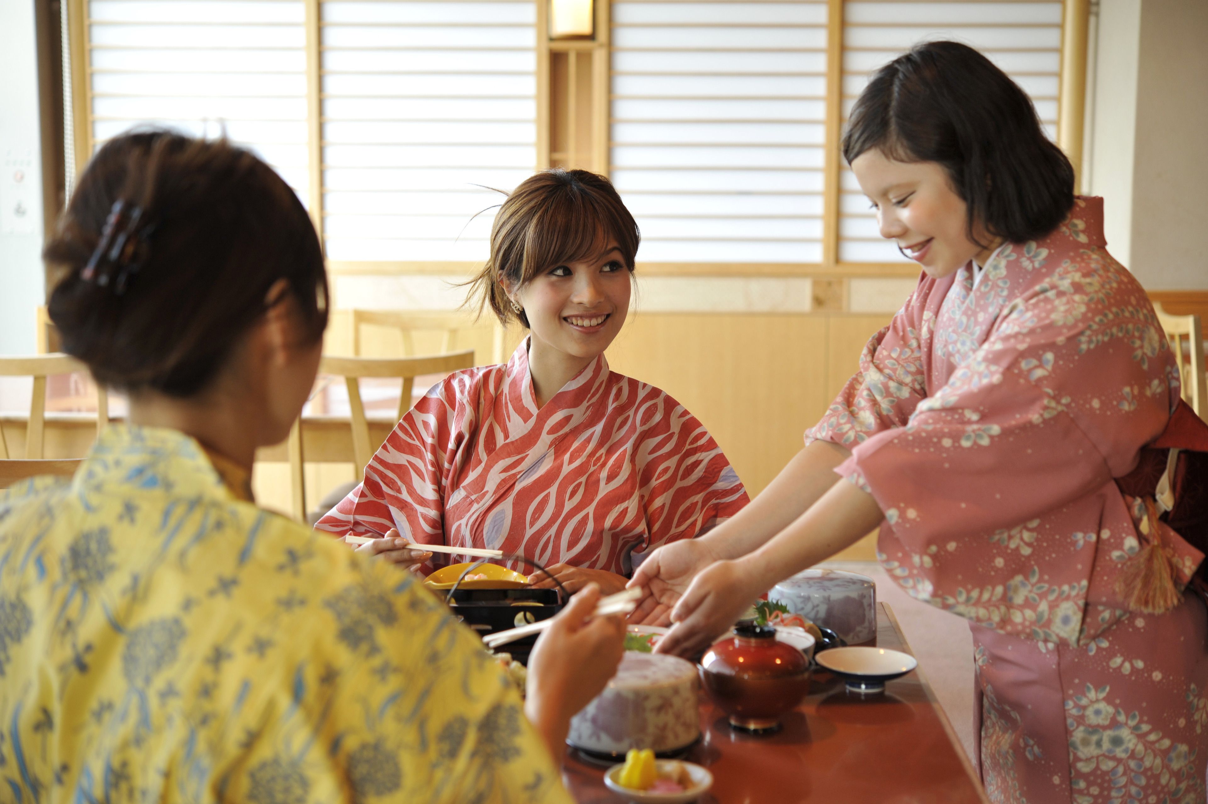 A traditional Japanese meal with chopsticks and a teapot on a wooden table.