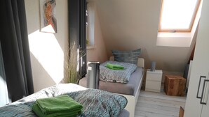 Ein gemütliches Schlafzimmer mit Bett, Nachttisch und einem kleinen Holzhocker.