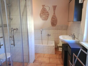 Un baño con cabina de ducha de vidrio, bañera, lavamanos e inodoro.