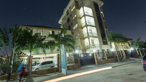 Un edificio de varios pisos con balcones, una entrada con reja y un cartel que indica una plaza.