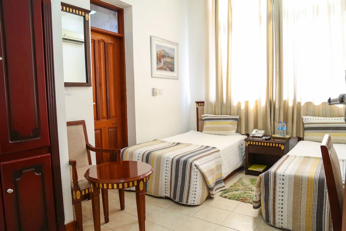 Une chambre d’hôtel avec deux lits, une porte en bois, une petite table et une chaise.
