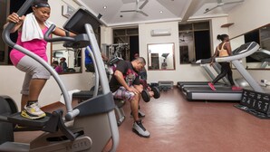Un gimnasio con cintas de correr, máquinas de pesas y un muro de espejos.