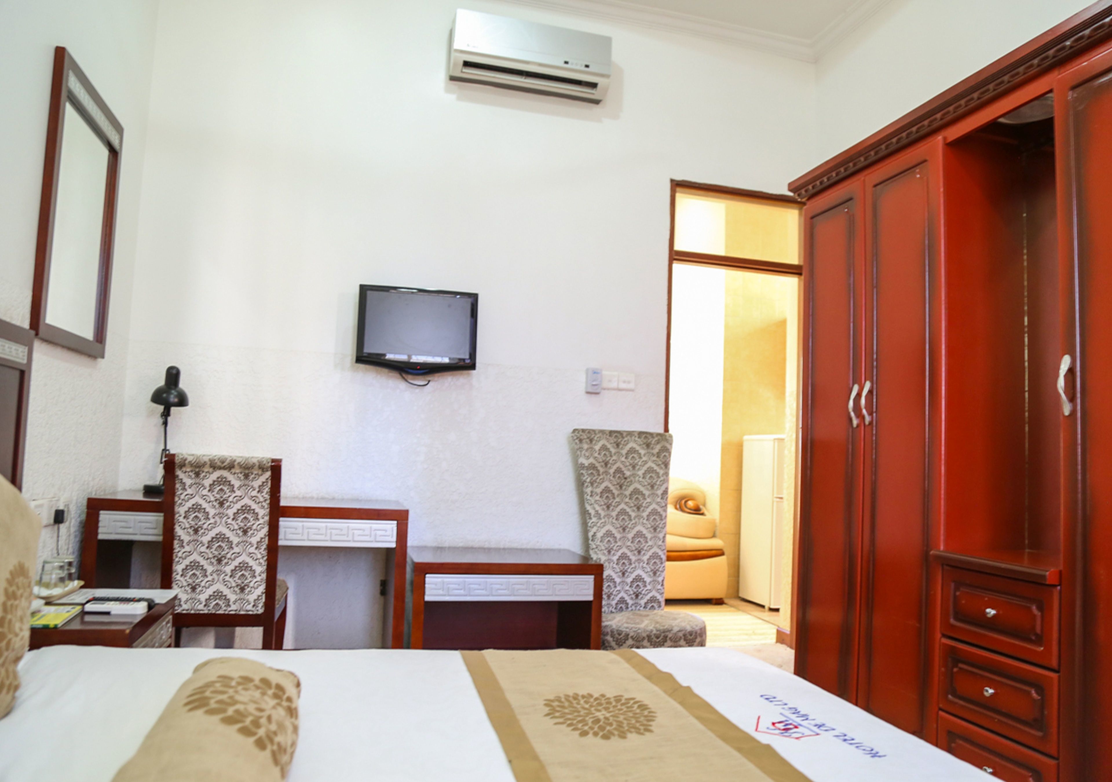 A hotel room with a bed, a desk, a television, and a wardrobe.