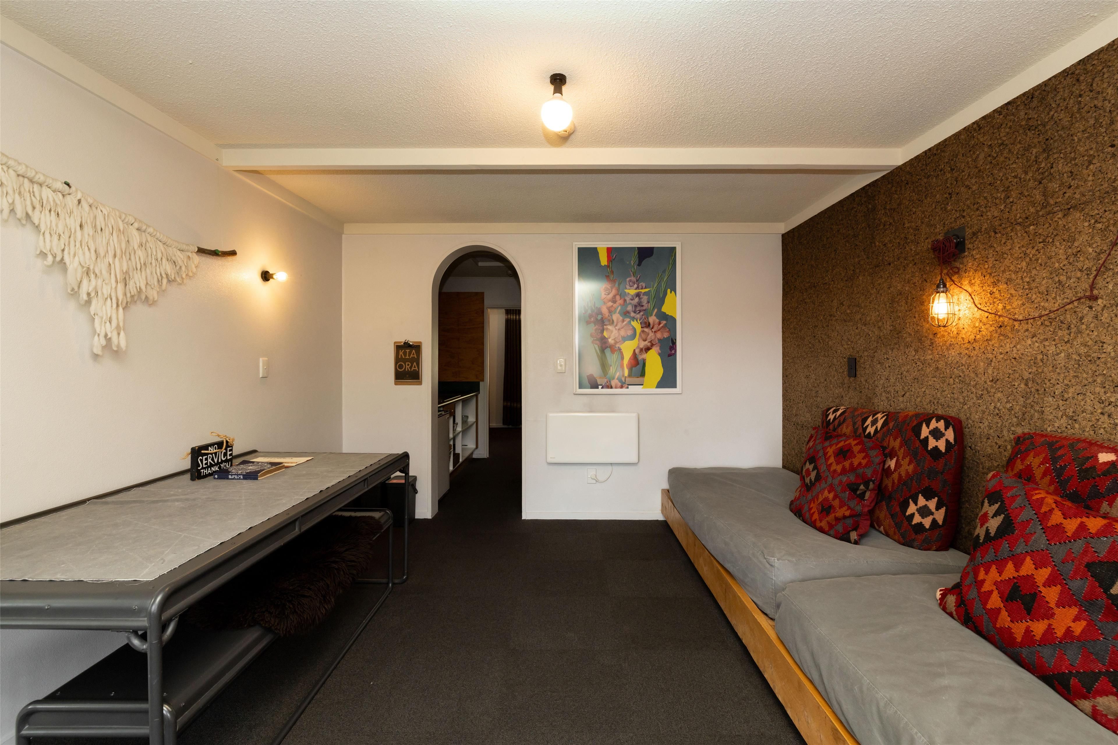 A compact room with a bunk bed, a desk, and a wall-mounted light fixture.