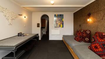 A compact room with a bunk bed, a desk, and a wall-mounted light fixture.